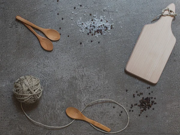 Wooden spoons, cutting board and clew on the stone background — Stock Photo, Image