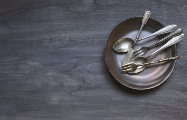 Koyu ahşap arka plan üzerinde antik çatal bıçak takımı ile plaka