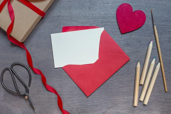 Roter Umschlag mit Bleistiften und Holzherz — Stockfoto