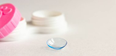 Gri arka planda kontak lens, bavul ve cımbız. Seçici odaklanma. Kapat.