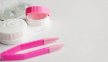 Gri arka planda kontak lens, bavul ve cımbız. Seçici odaklanma. Kapat.