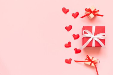 Birkaç el yapımı hediye kutusu, kurdele, fiyonk ve pembe arka planda küçük kırmızı kalpler. Hediye verme kavramı, sevgi, sevgililer günü. Uzayı kopyala, düz olarak