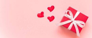 Beyaz kurdeleli kırmızı hediye kutuları ve pembe arka planda küçük kırmızı kalpler. Hediye verme kavramı, sevgi, sevgililer günü. Uzayı kopyala, düz, afiş