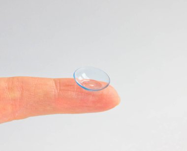 Gri arka planda insan parmağındaki kontakt lens. Seçici odaklanma. Kapat.