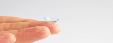 Gri arka planda insan elinin kontakt lensi. Seçici odaklanma. Kapat.