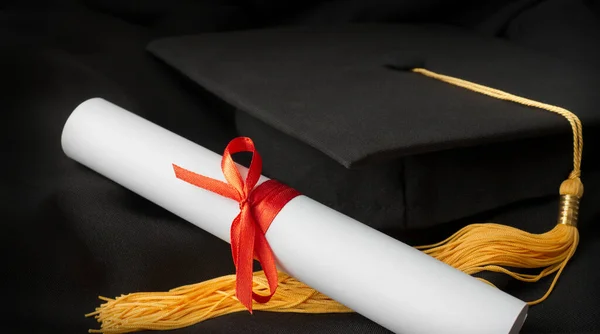 graduation cap and diploma close up on black