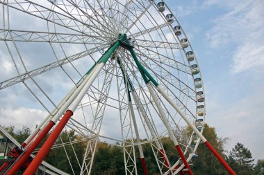 Parktaki dönme dolap mavi bulutlu dramatik gökyüzüne karşı. Dikey fotoğraf