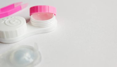 Gri arka planda kontak lens, bavul ve cımbız. Seçici odaklanma. Kapat.