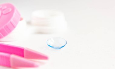 Gri arka planda kontak lens, bavul ve cımbız. Seçici odaklanma. Kapat.