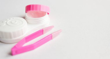 Gri arka planda kontak lens, bavul ve cımbız. Seçici odaklanma. Kapat.