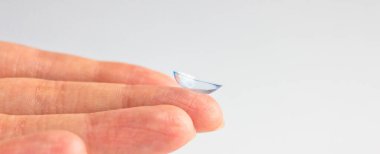 Gri arka planda insan elinin kontakt lensi. Seçici odaklanma. Kapat.