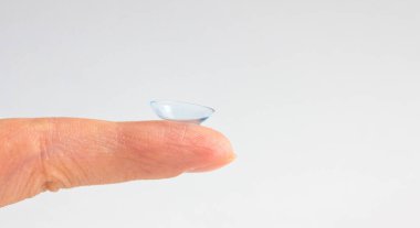 Gri arka planda insan parmağındaki kontakt lens. Seçici odaklanma. Kapat.