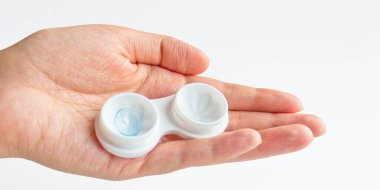 Gri arka planda kadın eli lensli açık lens kutusu. Seçici odak