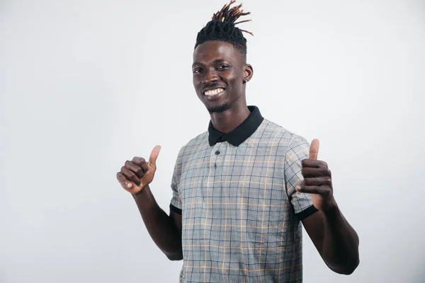 Retrato de um homem alegre, positivo, bonito com pele preta, um sorriso radiante em uma camisa, dando um polegar para cima com um dedo para a câmera, isolado em um fundo cinza — Fotografia de Stock