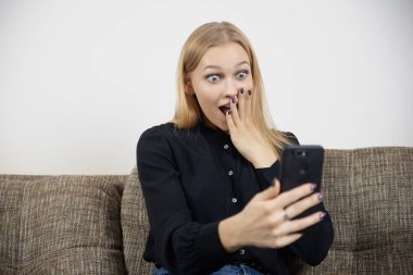 Mutlu, heyecanlı genç bayan telefonuna bakıyor. Alışveriş, satış teklifi ve iyi haberler konusunda hayrete düşmüş.