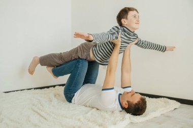 Baba oğul gülümser ve birlikte oynarken eğlenirler. Küçük bir çocuk bir kuş ve bir uçağın uçuşunu canlandırıyor..