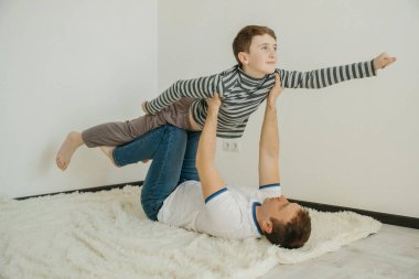 Baba oğul gülümser ve birlikte oynarken eğlenirler. Küçük bir çocuk bir kuş ve bir uçağın uçuşunu canlandırıyor..