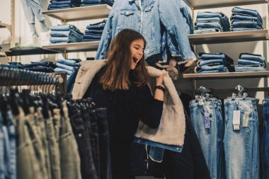 Kız alışveriş mağazasında'deki seçerek yeni kot gülümseyen.