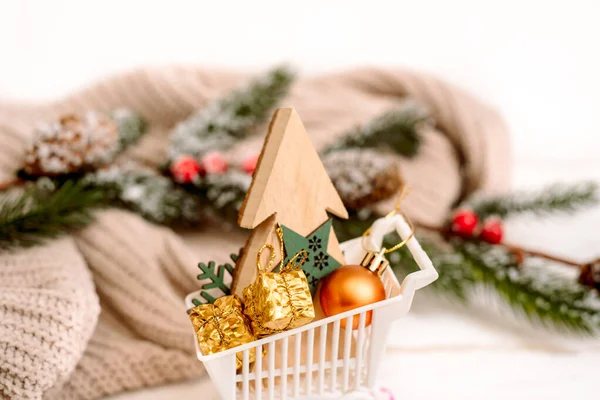 圣诞礼品盒在购物车与装饰雪地周围，圣诞销售的概念。舒适的针织毛衣. — 图库照片
