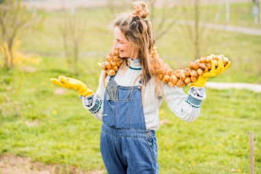 Kot pantolon giymiş gülümseyen kadın çiftçi bahçede elinde yeşil soğan tutuyor. Bir sürü ampul. Ampul dikmek ve hasat yapmak. Sebze buketi