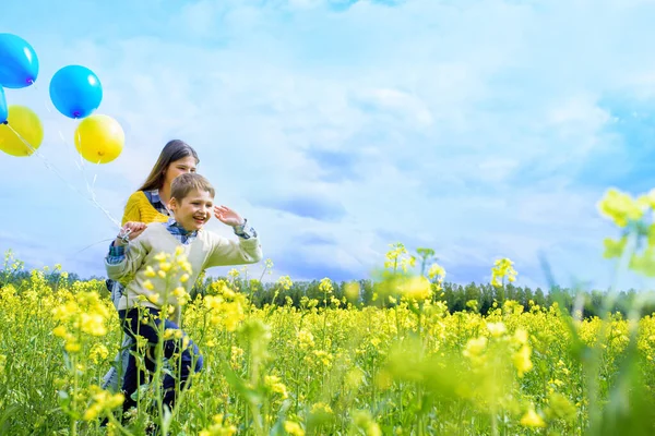 Menina feliz com azul e amarelo. Campo amarelo de colza. crianças felizes correndo. conceito liberdade, verão. A colza é uma energia alternativa. — Fotografia de Stock