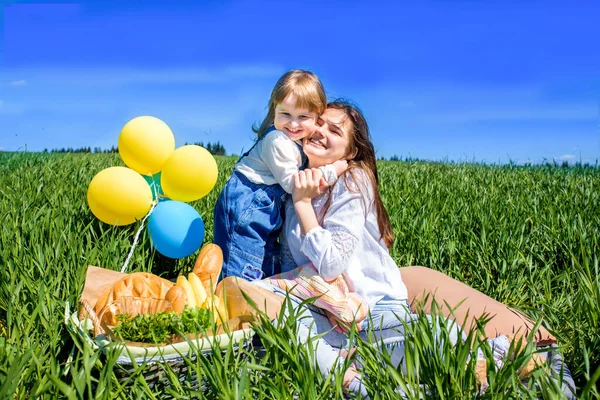 Les enfants en pique-nique. journée chaude d'été. sur le terrain. horizon, ciel bleu, herbe verte, fruits et pain blanc dans un panier. bonne enfance. deux filles soeurs. adolescent et bébé. — Photo