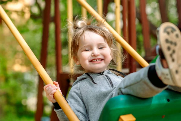 Menina bonito em um balanço seesaw no playground.Cute bebê menina em um balanço de baloiço. no parque infantil no parque ao ar livre. caminhada no jardim de infância — Fotografia de Stock