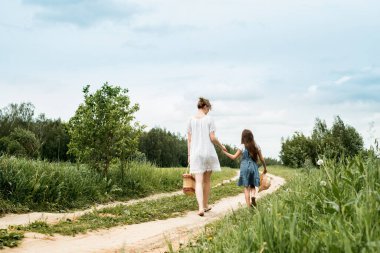 Açık hava yolu boyunca ormanda bir aile. Genç anne ve küçük kızı güzel bir sonbahar parkında. Kız çocuk ve çizmeli güzel bir kadın yürüyor ve eğleniyor.