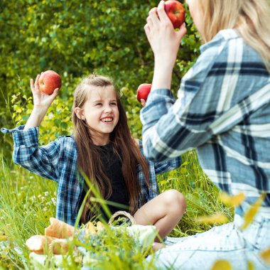 Küçük kızı ve ailesi parkta piknikte. Anne çocuğunu seviyor. Yaşam tarzı. Güzel bir yaz gününde mutlu bir aile. Şefkat ilişkileri