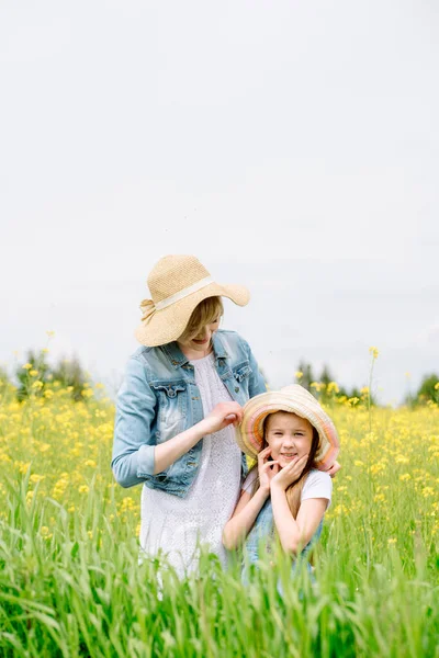 Outdoor walk. summer in field. yellow flowers.Mom hugs her daughter, regrets and protects. upbringing and care. nature,summer day vacation. playing sunset time. friendly family. — Fotografia de Stock