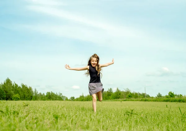 Kid girl jumping on the grass at spring.Summer field, horizon and sky. Happy childhood and freedom.Life Style Outdoors. — Stock Photo, Image