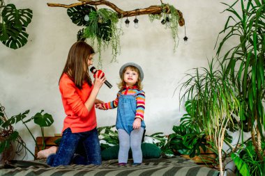 Geleceğin yıldızları en sevdikleri şarkıyı söylüyor. Çocuklar evde, yatakta şarkı söylüyor. Aile aktiviteleri ve ablasıyla ebeveynlik. Güzel bir iç mekan. Egzotik İç Bitkiler.