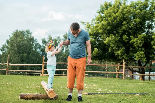 Jogos ativos ao ar livre. O pai a brincar com a filha no parque. Campo, caminhe ao longo da estrada rural.Leva sua filhinha, segura a mão, — Fotografia de Stock