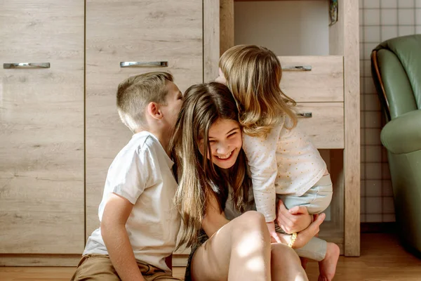 Tres niños juegan en casa. hermano y hermanas se ríen y se divierten. Homeliness es admiración y amor. Concepto familiar. — Foto de Stock