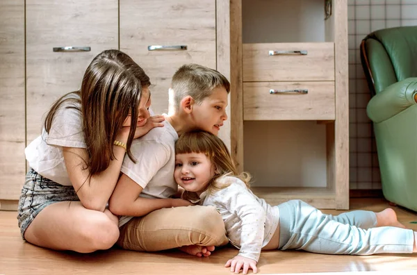 Tres niños juegan en casa. hermano y hermanas se ríen y se divierten. Homeliness es admiración y amor. Concepto familiar.Película granulada — Foto de Stock