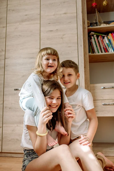 Los tres jugamos en casa y nos reímos. felicidad familiar. juego alegre en el suelo. dos niñas y hermano chico — Foto de Stock