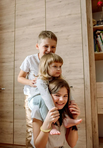 My tři si hrajeme doma a smějeme se. rodinné štěstí. radostná hra na podlaze. dvě dívky a bratr chlapec — Stock fotografie