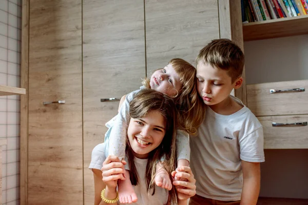 Tres niños están jugando en el suelo en casa. Feliz risa. El concepto de una familia feliz. Amor apasionado. — Foto de Stock