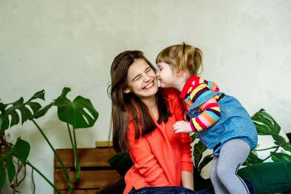 Il bambino carino sta pettinando vicino allo specchio. Ragazza felice si sta divertendo nella stanza dei bambini a casa sul letto. Piante d'appartamento esotiche. Plaid verde e grigio. assistenza infermieristica. Il concetto di amore familiare. — Foto Stock