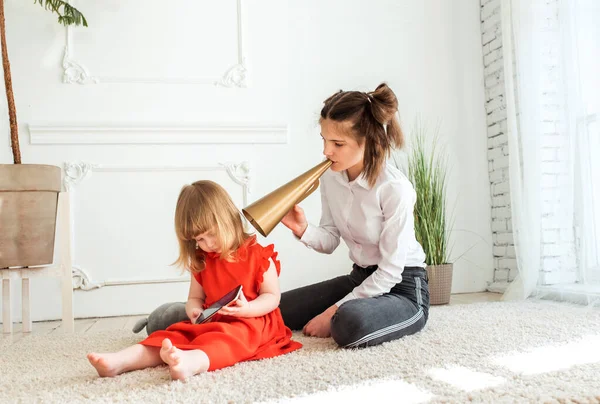 Dos hermanas juegan en el teléfono. anticomunicación. Ellos no saben cómo comunicarse, mala comunicación.niñas se alejaron el uno del otro. no se ven, se escuchan, entienden uno de uno — Foto de Stock