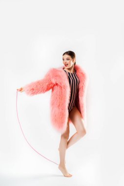 Sırtında beyaz sırt çantası ve gözlüklü neşeli, koyu renk saçlı kadın izole bir zeminde koşuyor. Portakal rengi yağmurluk ve elinde su şişesi tutan spor şortlu kızın portresi.