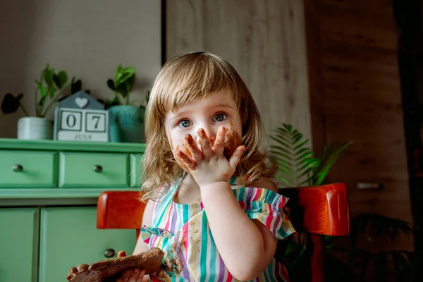 Bebê manchado comendo chocolate pela primeira vez. Dia de Chocolate 07 de julho — Fotografia de Stock