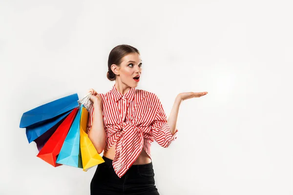 Femme commerçante tenant des sacs à provisions sur blackin un studio. Magnifique jeune acheteur caucasien souriant heureux. Emotionnel et heureux, aime les ventes, court et crie sur ses achats — Photo