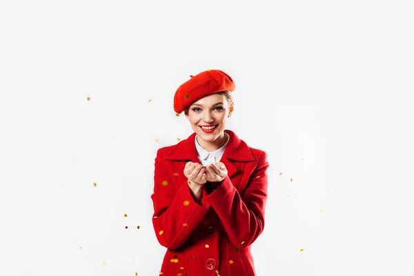Krásná dívka v červeném kabátě a červený baret foukající kouzelné hvězdy. dovolená, létání jiskry a tinkel. Narozeninová oslava na Valentýna nebo Vánoce — Stock fotografie
