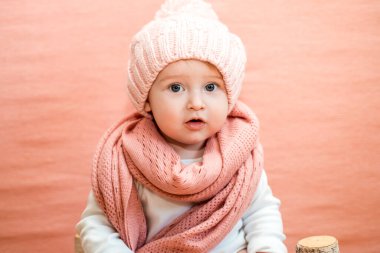Küçük kız örgü şapkalı ve gri atkılı.