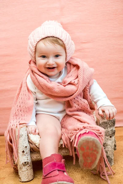 Zbliżenie twarzy dziecka w snodzie. Cute baby girl z niebieskimi oczami w różowym dzianiny kapelusz i szalik na różowym tle.cozy ciepłej zimy lub wiosny — Zdjęcie stockowe