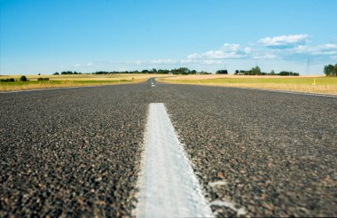 Ufuk çizgisine asfalt yol. Yeşil alanlar. mavi bulutsuz gökyüzü