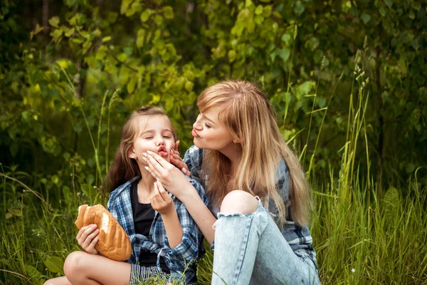 Mãe e filha estão brincando e se divertindo juntos. Piquenique na floresta. parque de verão, cesta de frutas, pão branco. Ao ar livre. Férias em família e união. — Fotografia de Stock