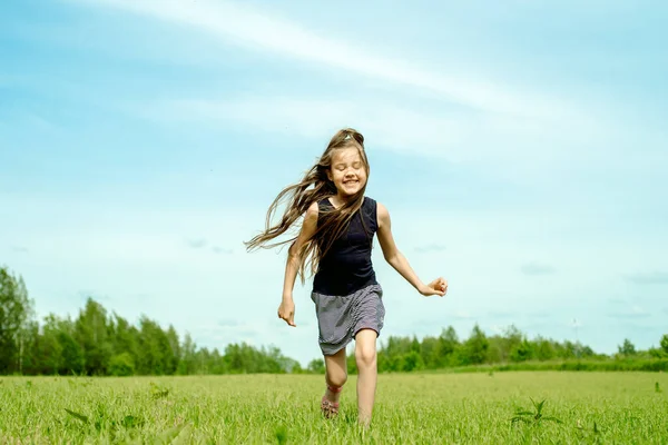 Маленькая девочка бежит по лугу в поле цветов, свобода, счастье и ветер в ваших волосах. — стоковое фото