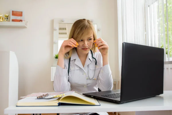 young stressed woman doctor sitting in modern office.tired doctor at the computer. online consultation.